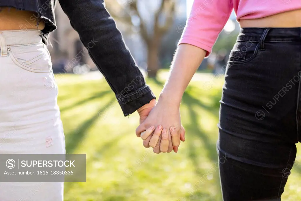 Female friends holding hands in public park