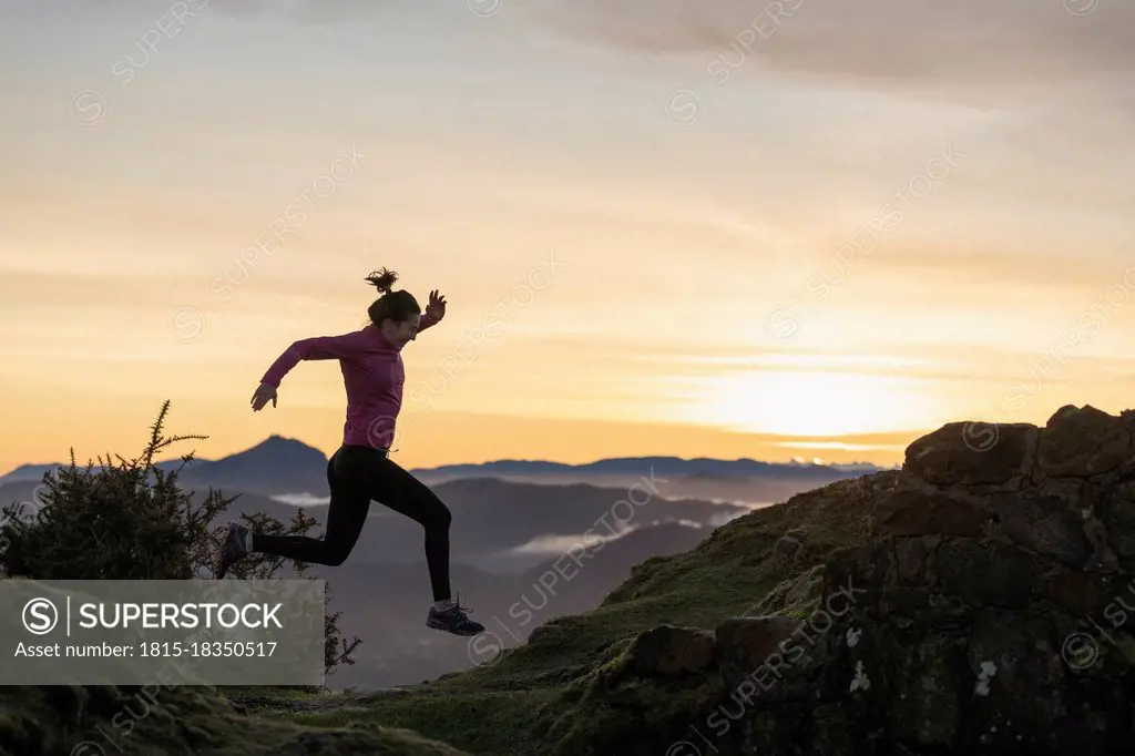 Young woman jumping while running during sunrise