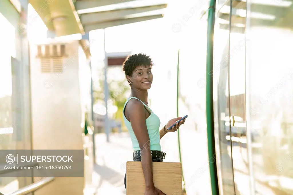 Young young woman standing at tram entrance with wireless technologies