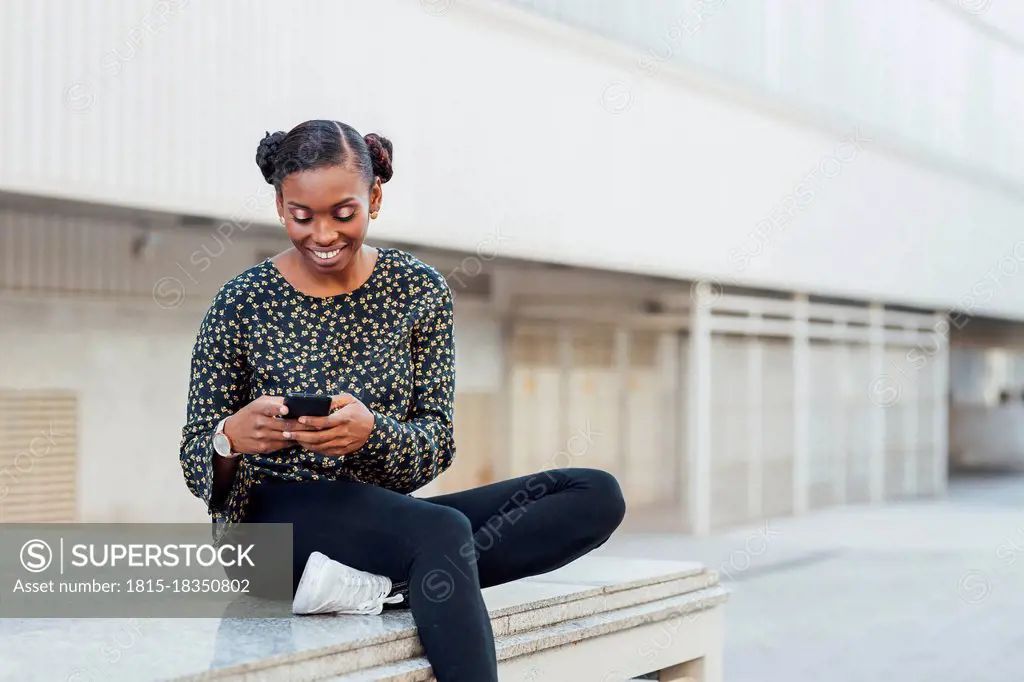 Mid adult woman smiling while using mobile phone