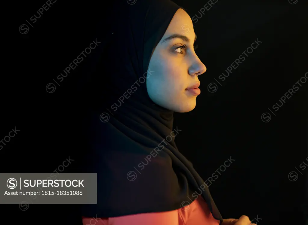 Young Arab woman with headscarf against black background