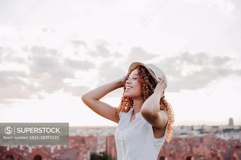 Happy Hispanic woman wearing hat against sky