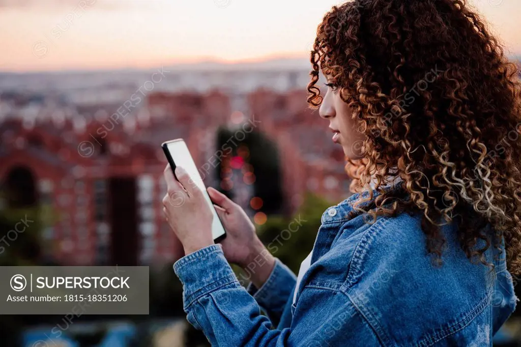 Hispanic woman using smart phone during sunset