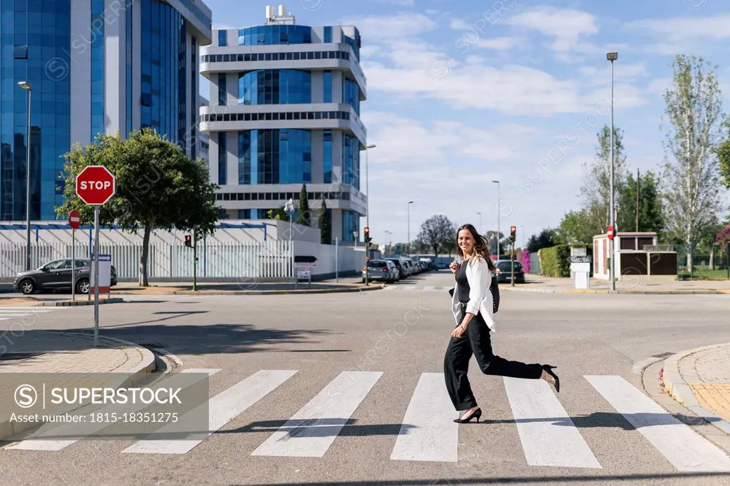 Businesswoman running on road during sunny day