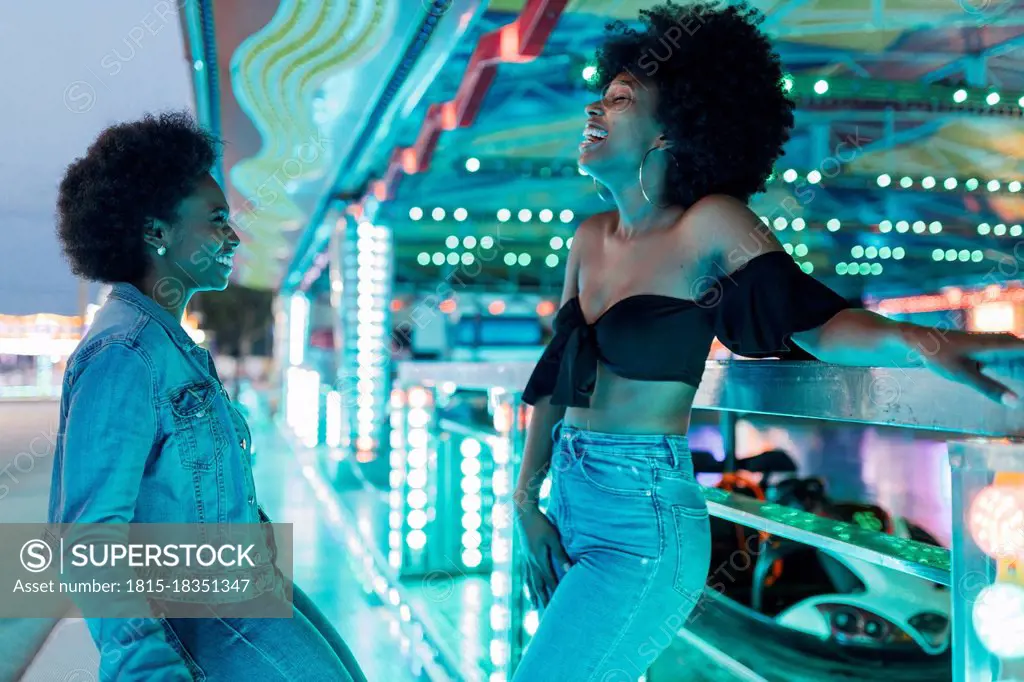 African female friends talking with each other in amusement park at dusk