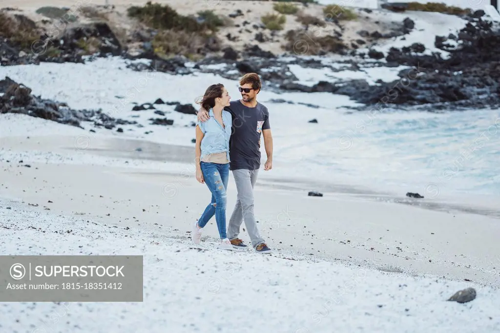 Mid adult couple talking while walking at beach