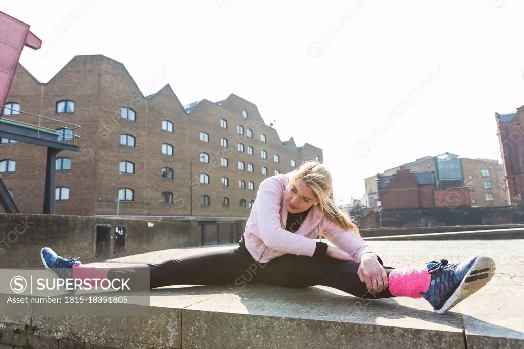 Blond young woman stretching while doing splits