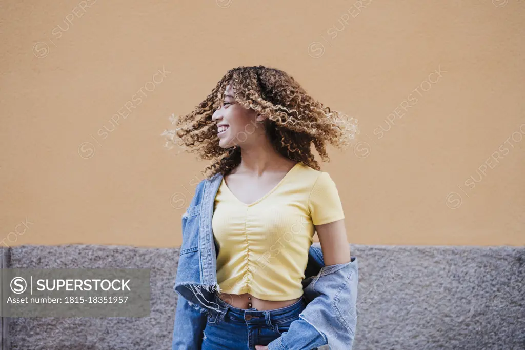 Beautiful woman with tousled hair by wall