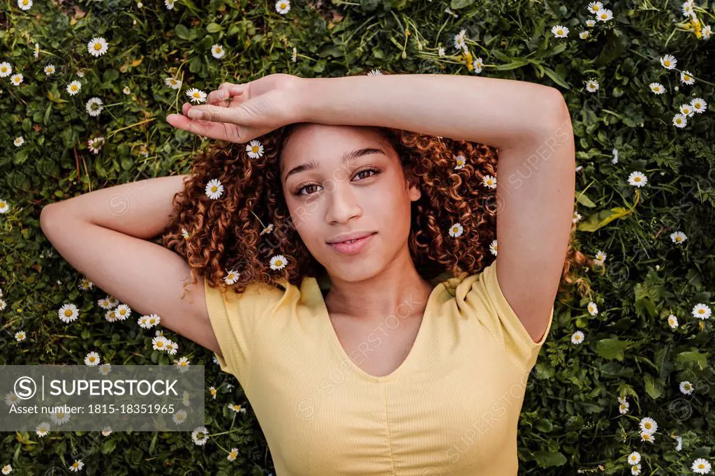 Woman with flowers in hair lying on meadow