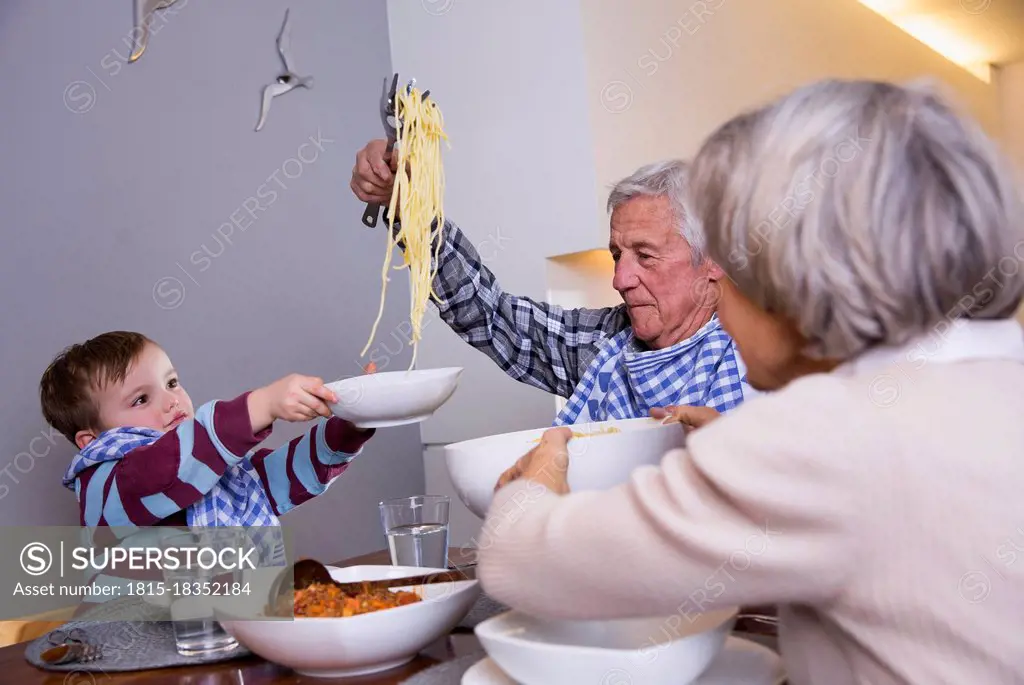 Boy giving food to man while sitting with woman at home