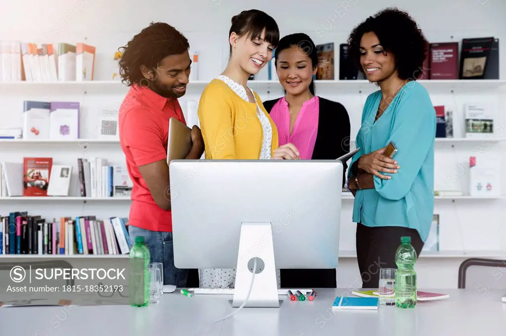 Smiling male and female entrepreneurs working in front of computer at office