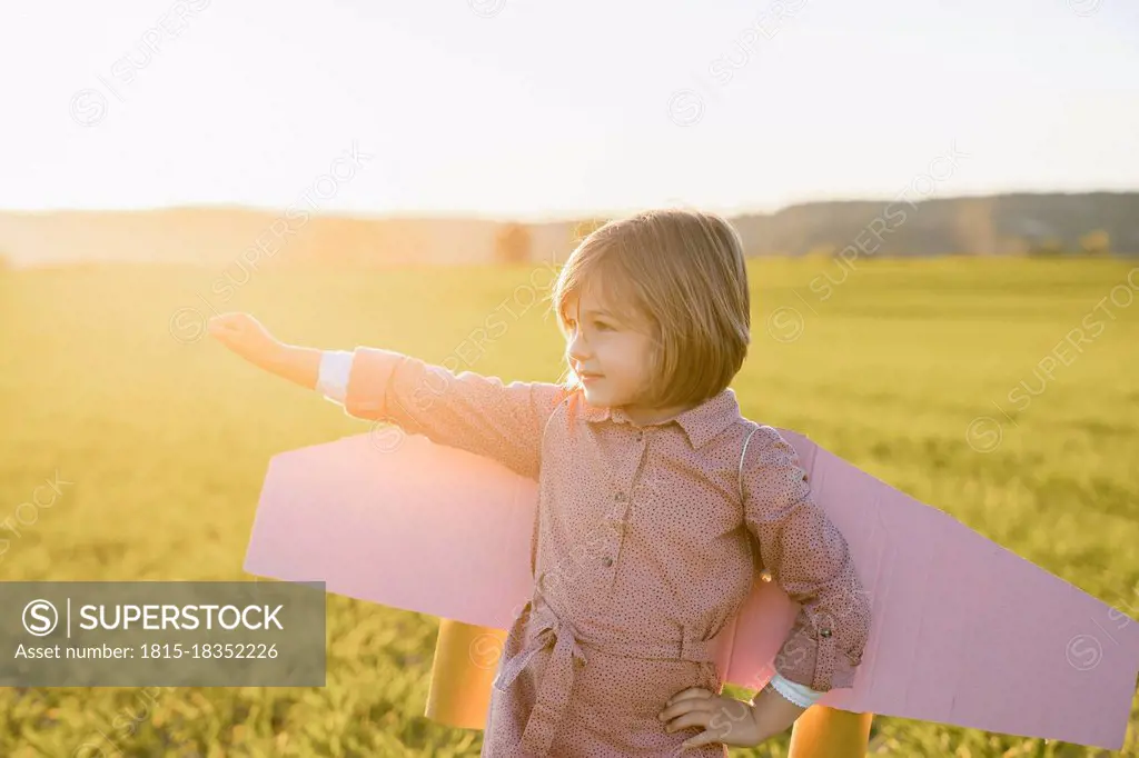 Little girl wearing rocket wings standing with hand on hip looking away