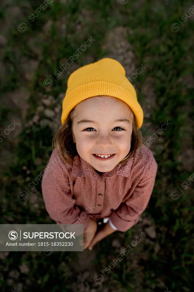 Smiling cute girl wearing knit hat standing on agricultural field