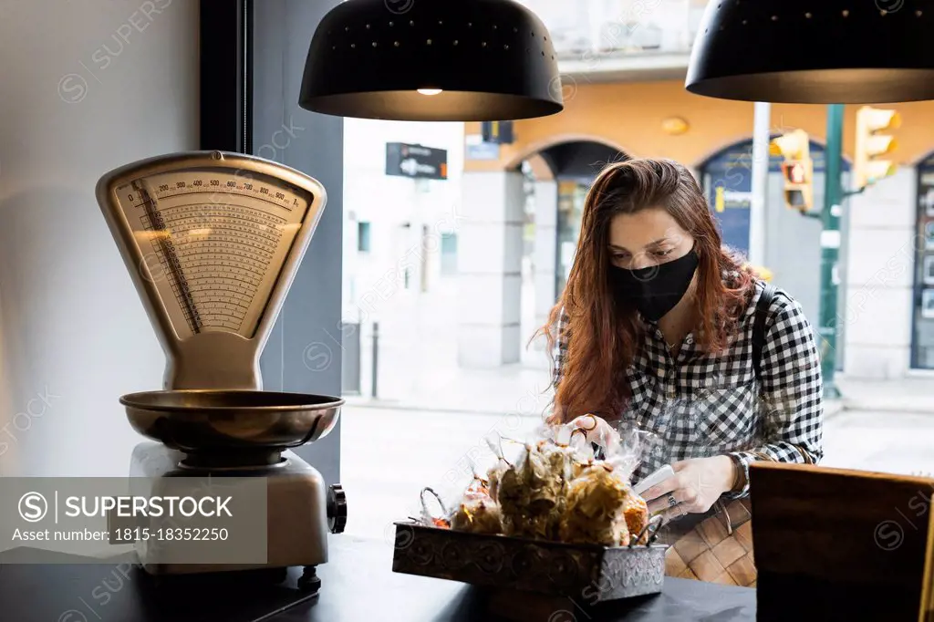 Woman wearing protective face mask taking food from counter at supermarket