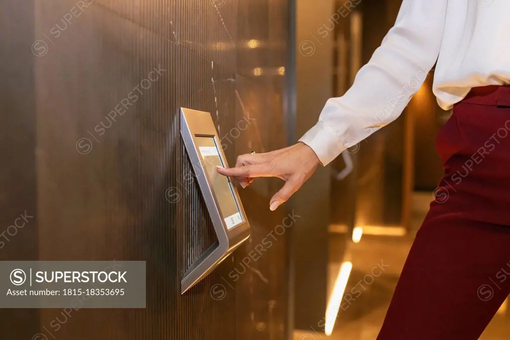 Female professional touching device screen at elevator