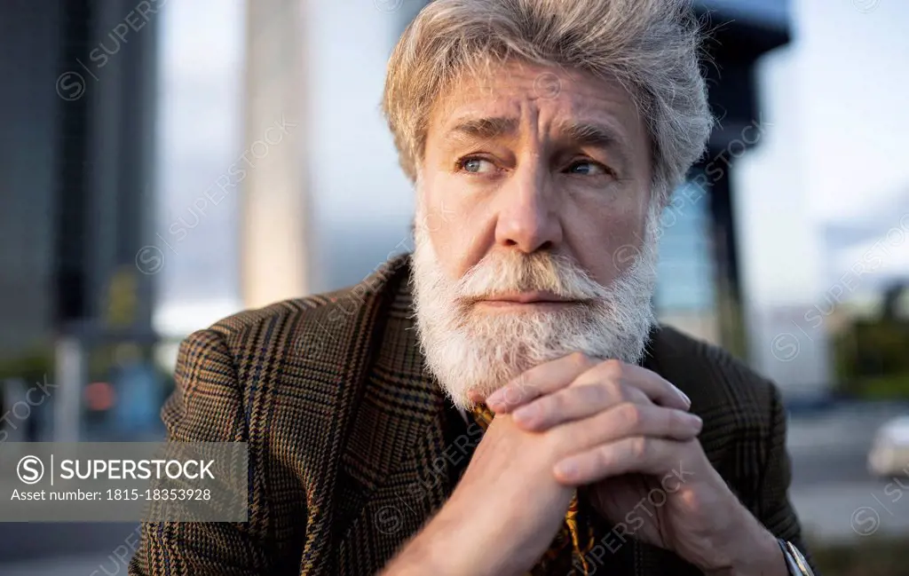 Thoughtful businessman with clasped hands on chin