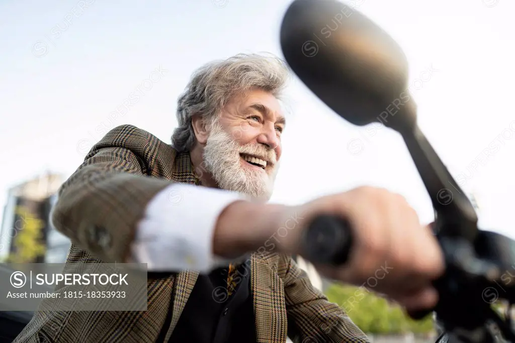 Cheerful mature businessman riding motorcycle