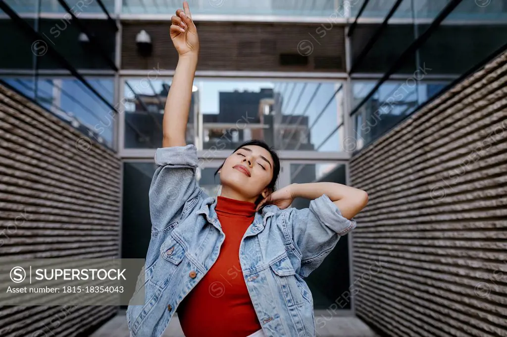 Woman with hand raised in front of building