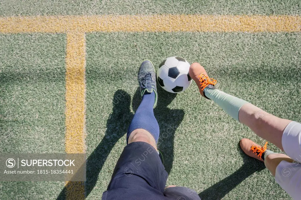 Father and son playing soccer at sports court