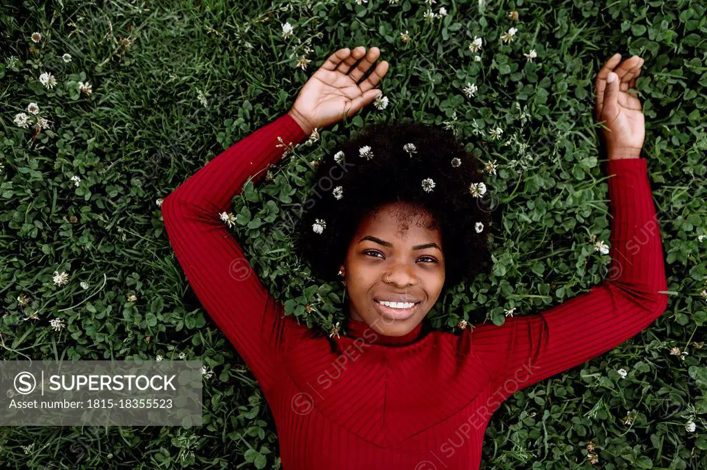 Young woman wearing flowers while lying on grass