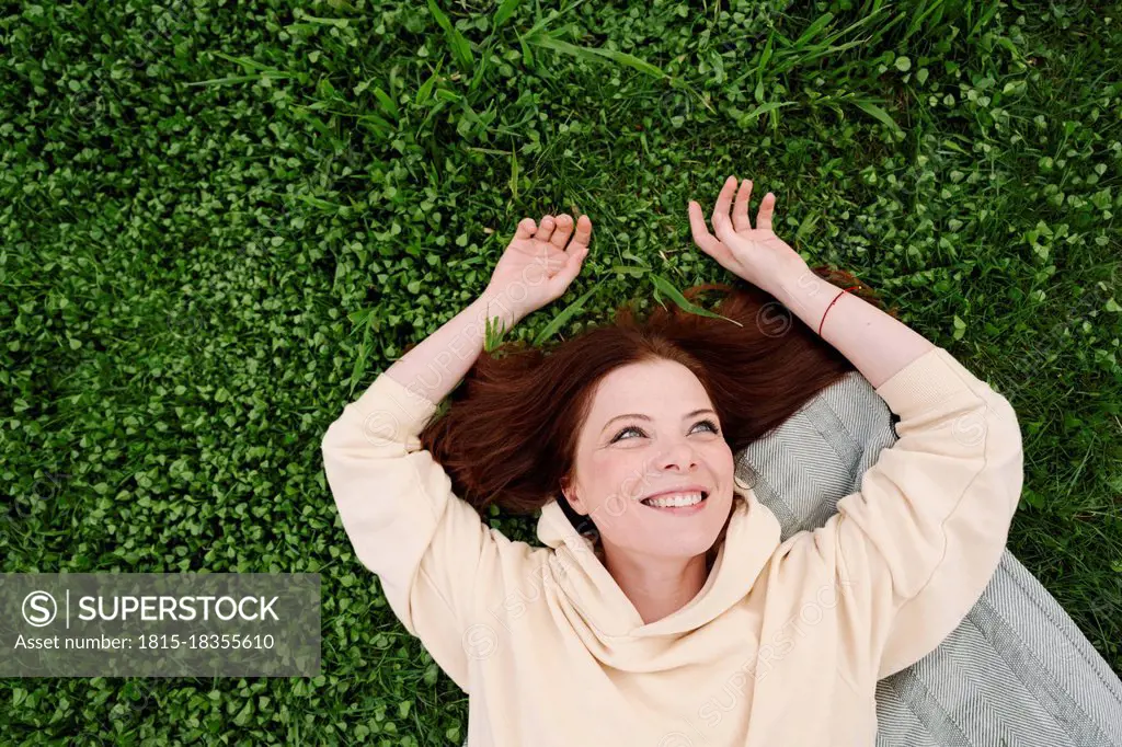 Happy mature woman lying on grass at public park