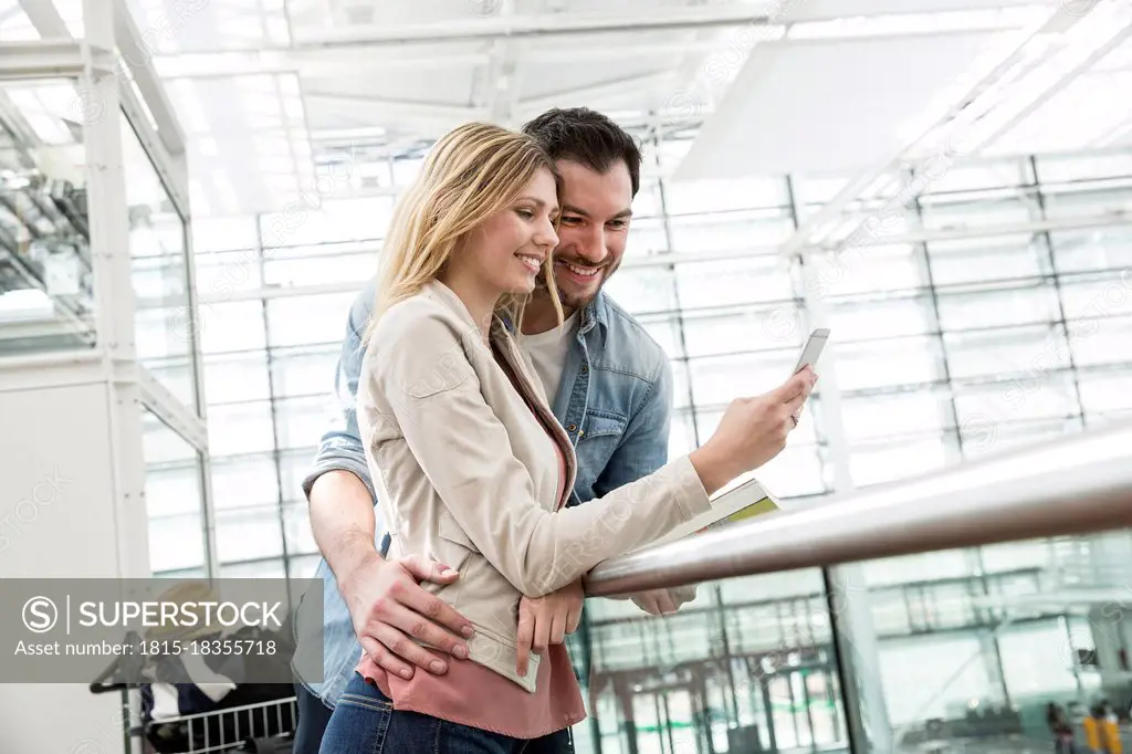 Young couple looking at smart phone in airport departure area