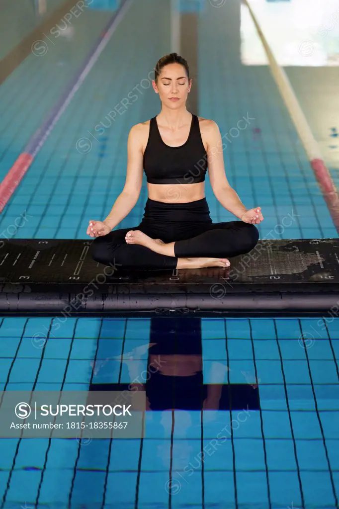 Mid adult woman in lotus position sitting on raft floating in swimming pool