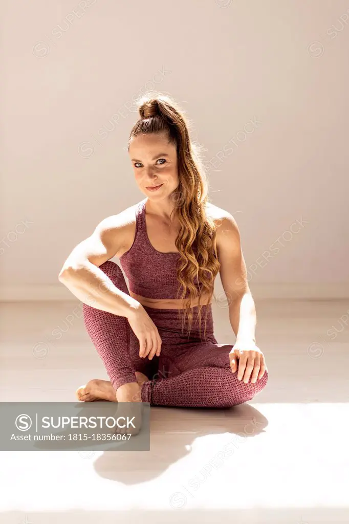 Smiling blond female athlete sitting at exercise room