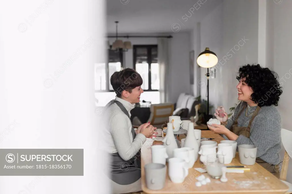 Female artists talking while working on craft product at workshop