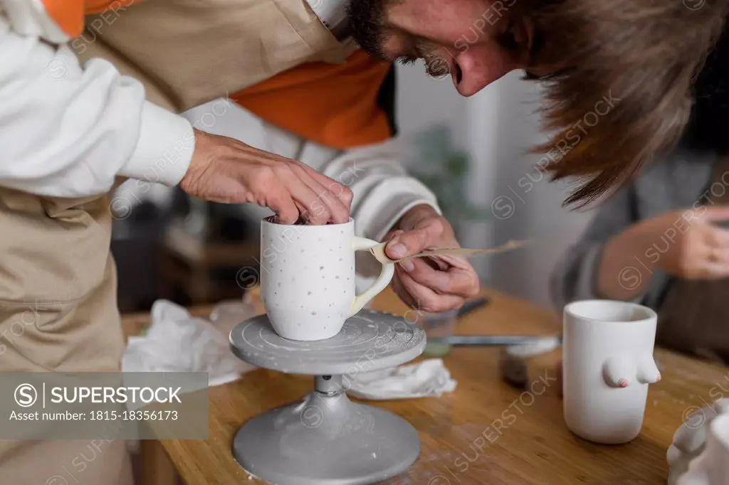 Male expert polishing cup with sand paper at workshop