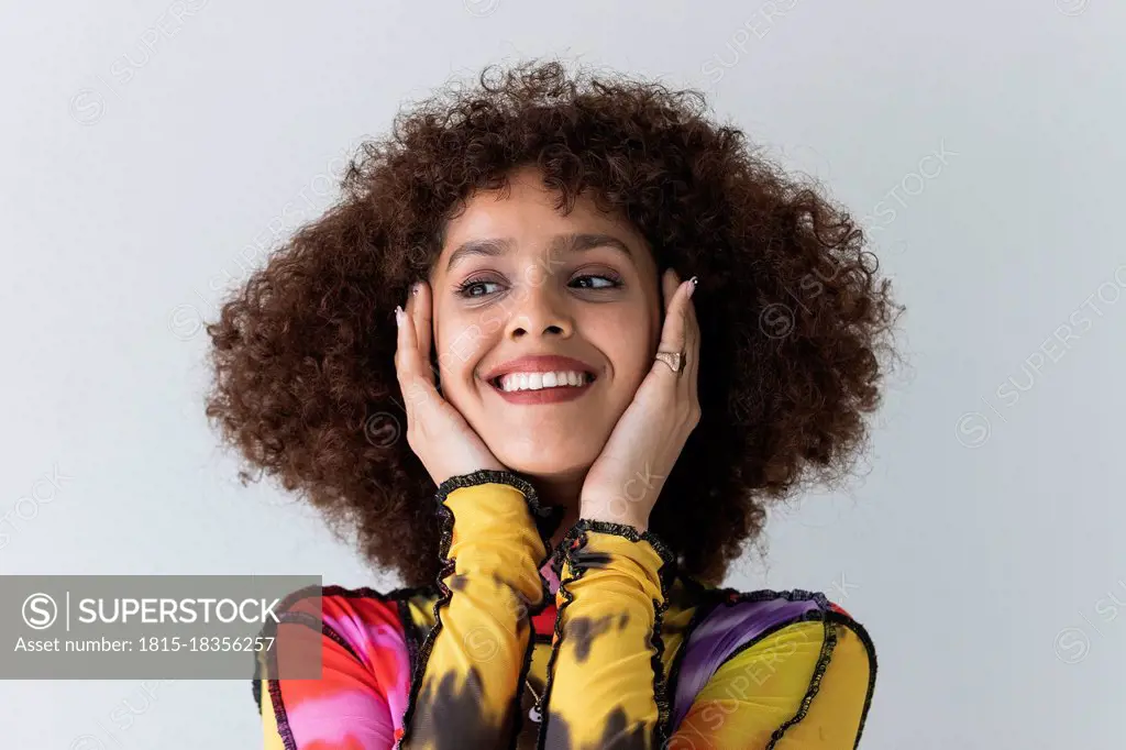 Curly hair woman smiling while looking away against white background