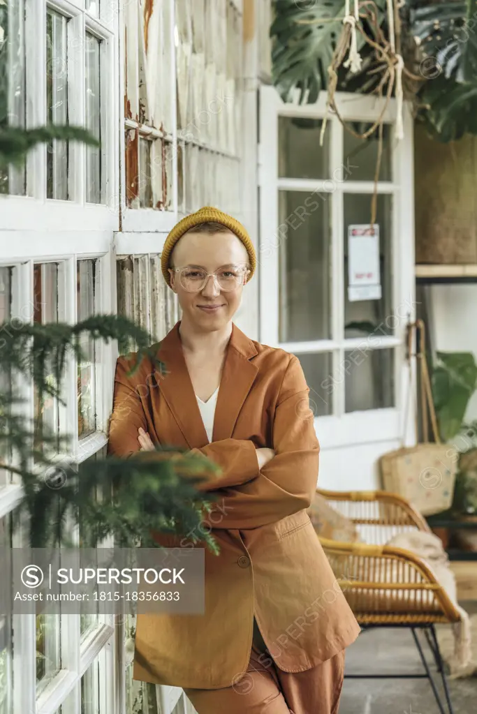 Young businesswoman with arms crossed at green office