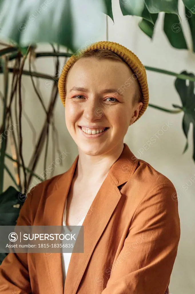 Smiling female entrepreneur in brown blazer at work place