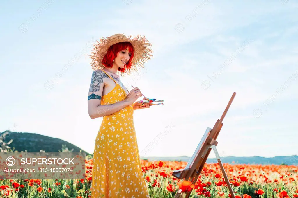 Smiling female artist looking at canvas on field