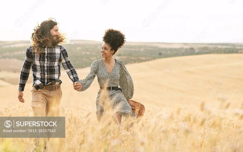 Couple looking at each other while walking on wheat field