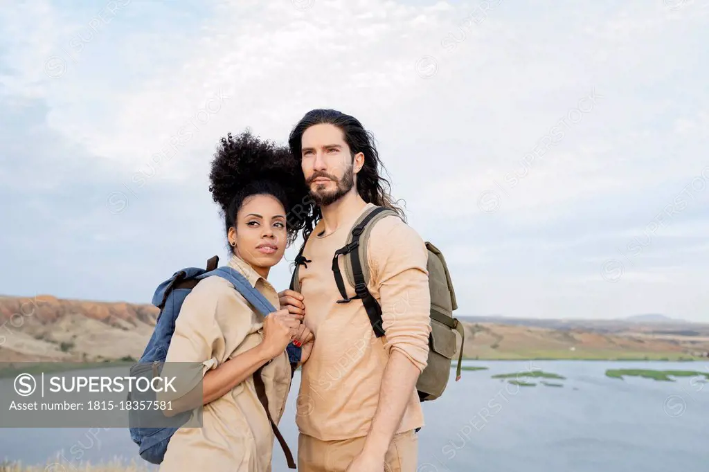 Girlfriend with backpack looking away while standing by boyfriend