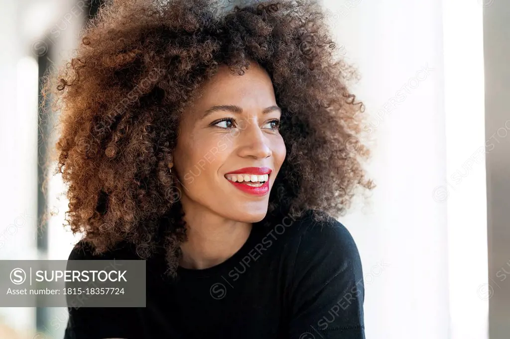 Smiling businesswoman with frizzy hair looking away in office