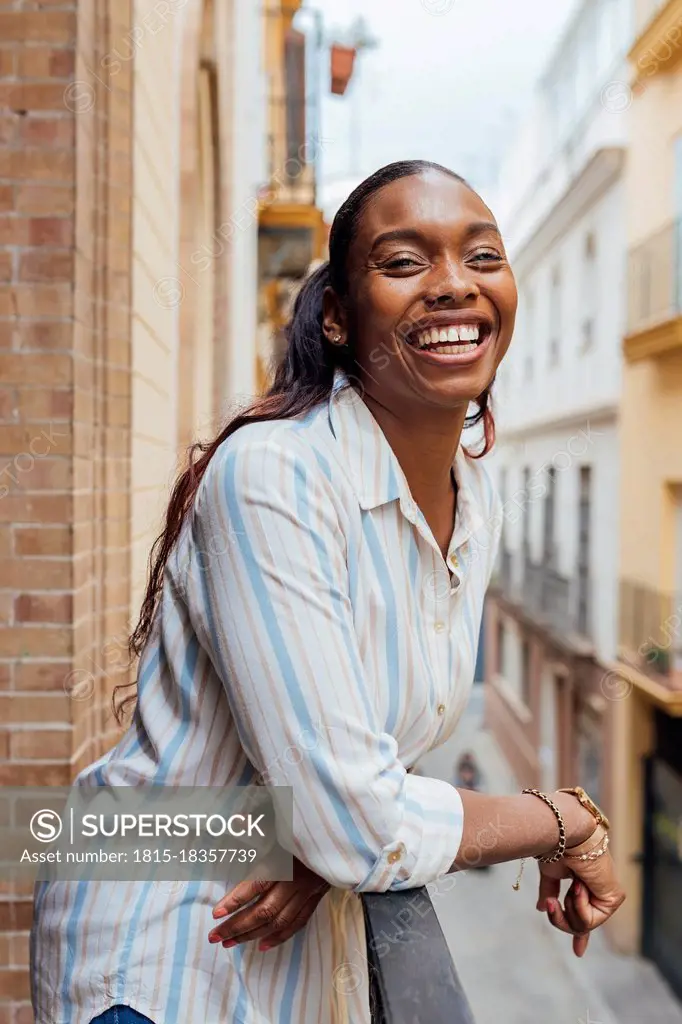 Cheerful woman leaning on railing in balcony