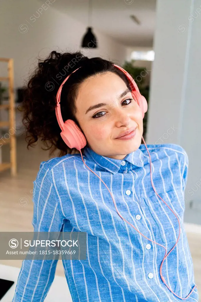 Smiling businesswoman with headphones listening music in office