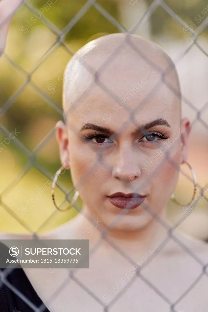 Serious transgender woman seen through chainlink fence