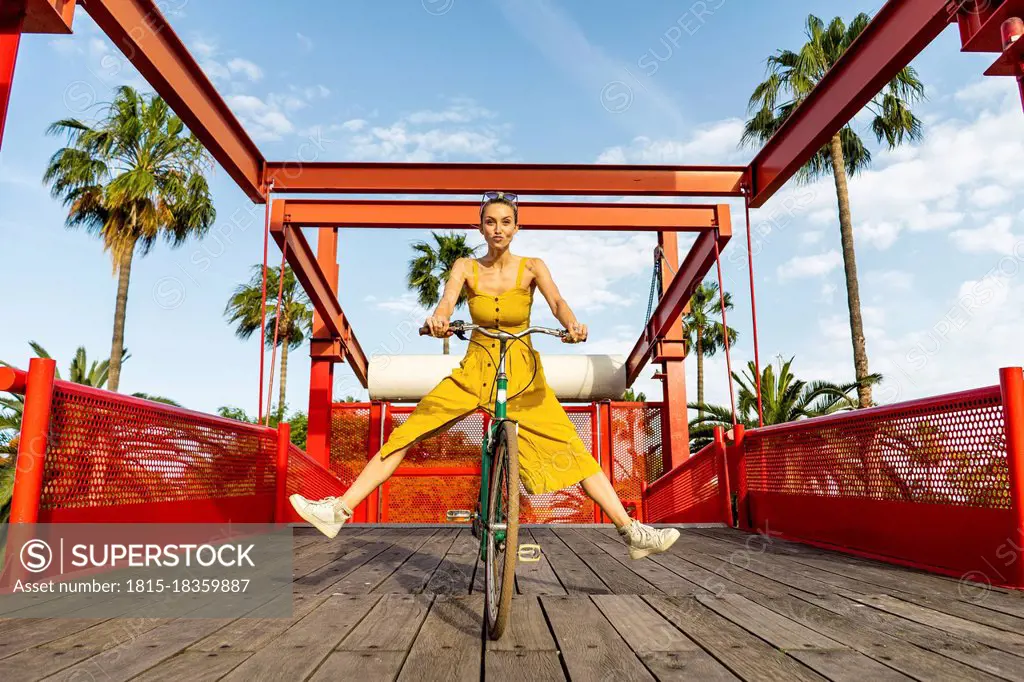 Carefree woman riding bicycle on sunny day