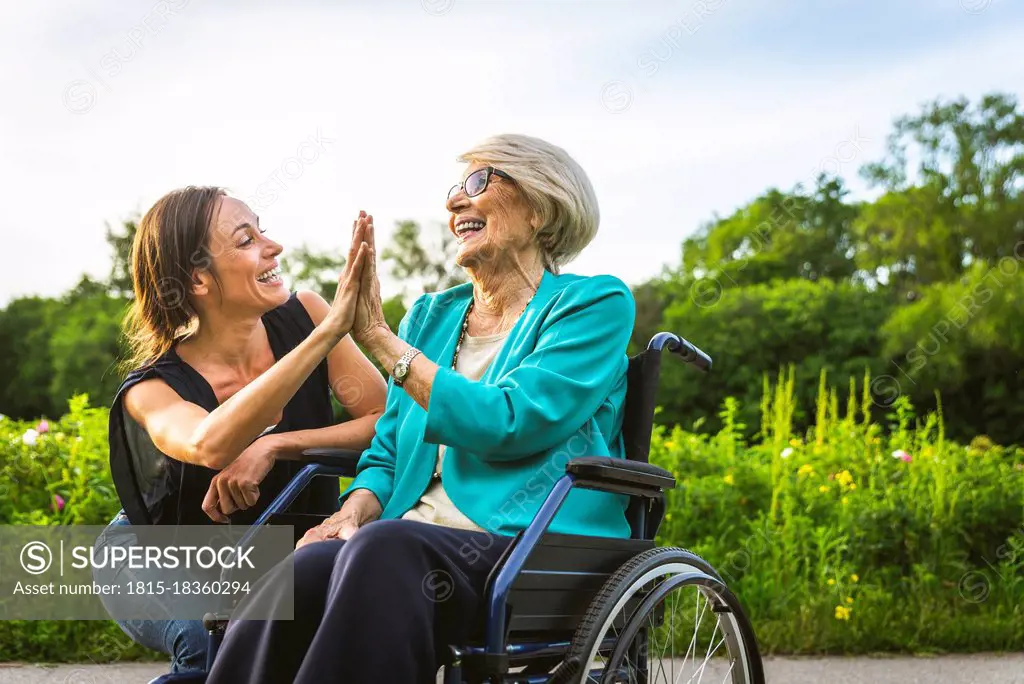 Happy granddaughter and grandmother giving high-five to each other at park