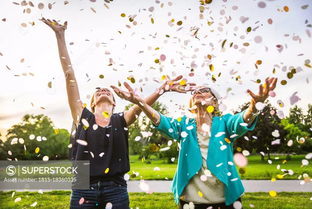 Granddaughter and grandmother playing with confetti at park