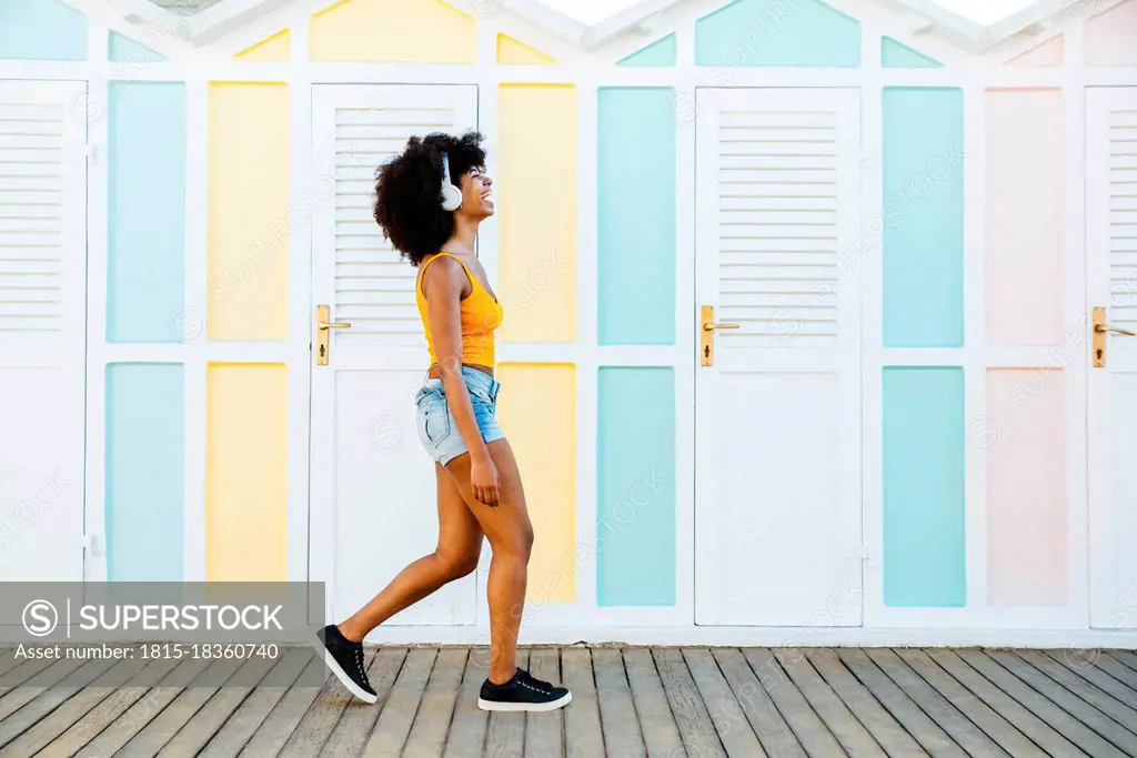 Cheerful woman walking by beach huts