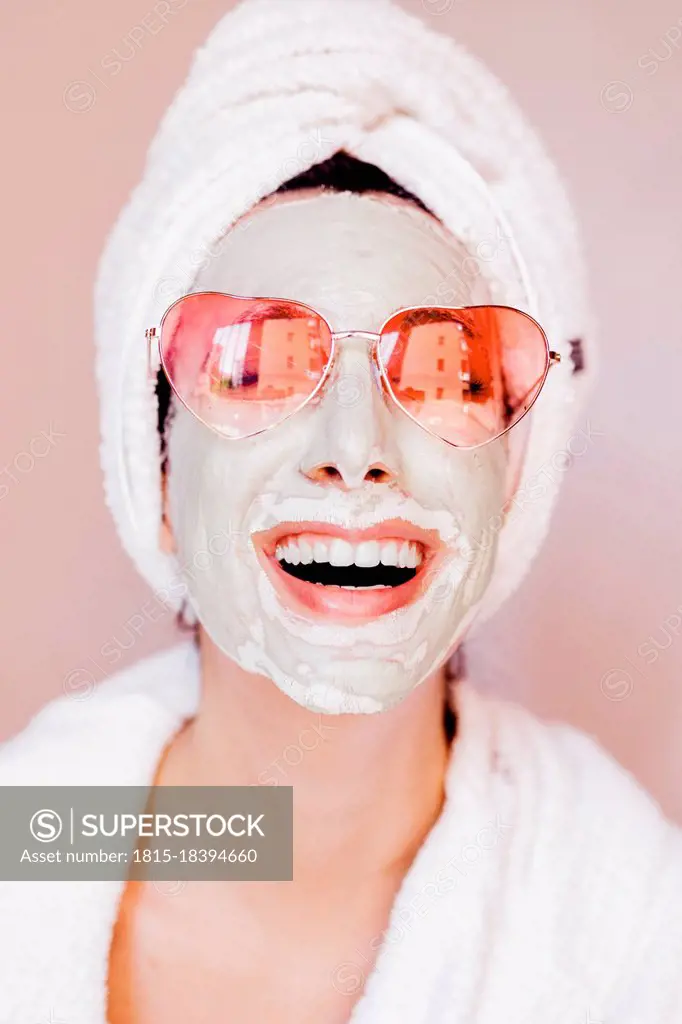 Happy young woman with beauty face mask wearing heart shape sunglasses