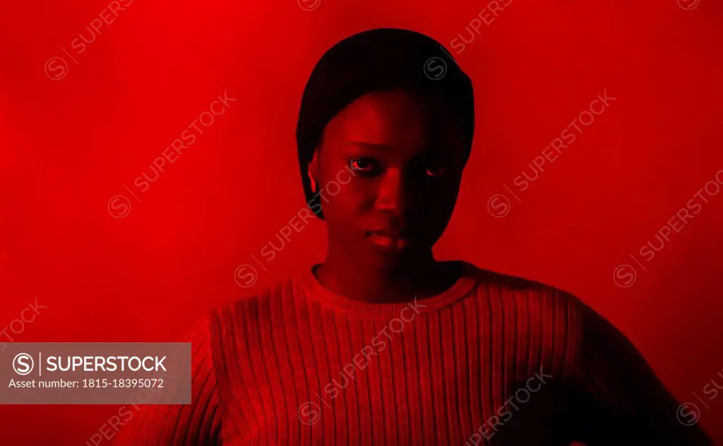 Serious woman staring in front of red background