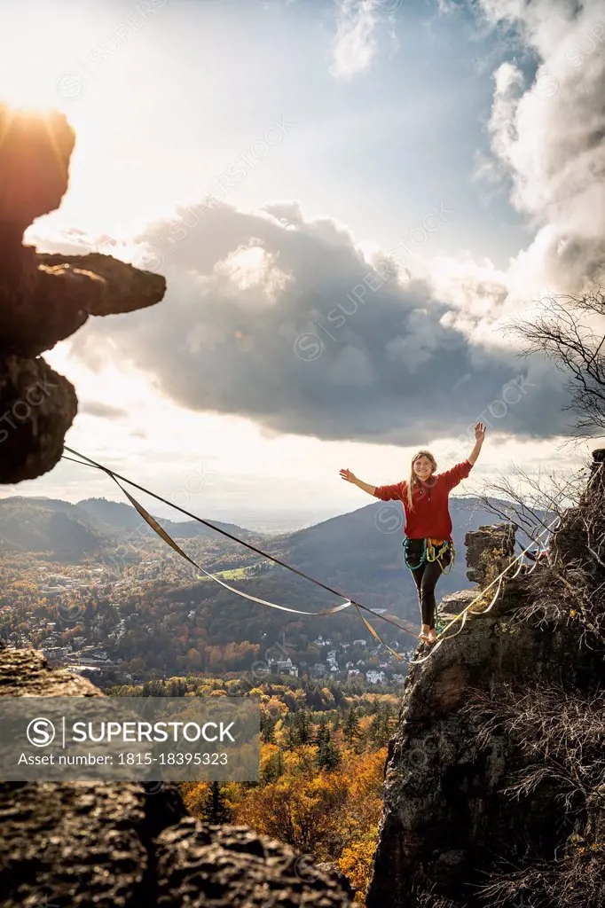 Woman with arms raised slacklining amidst mountains at Baden-Baden, Germany