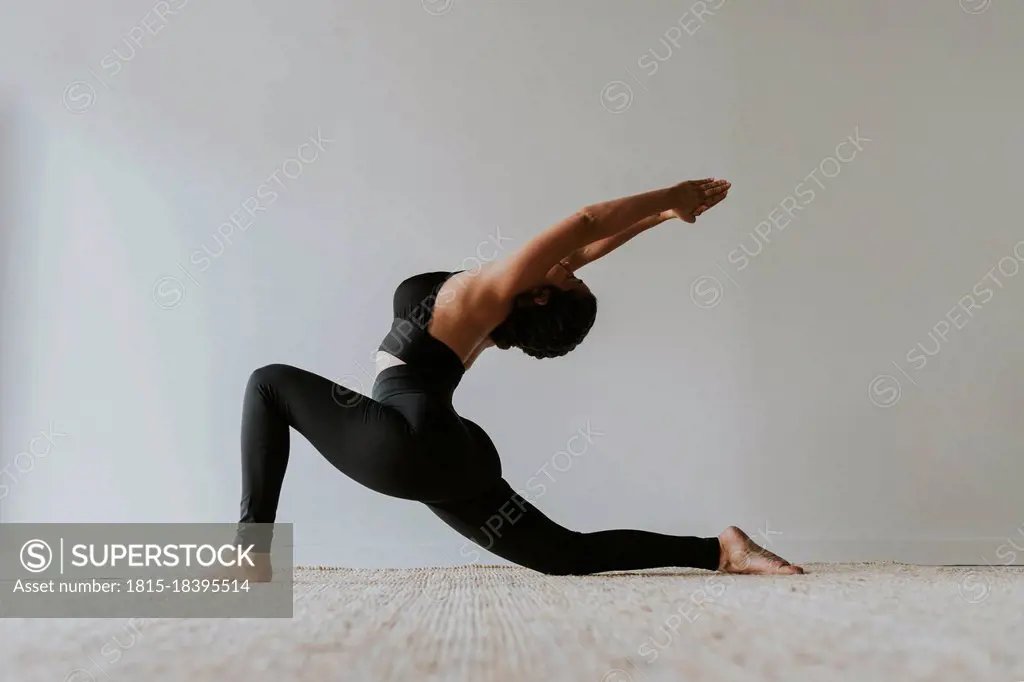 Female fitness teacher with arms raised bending backwards while practicing yoga