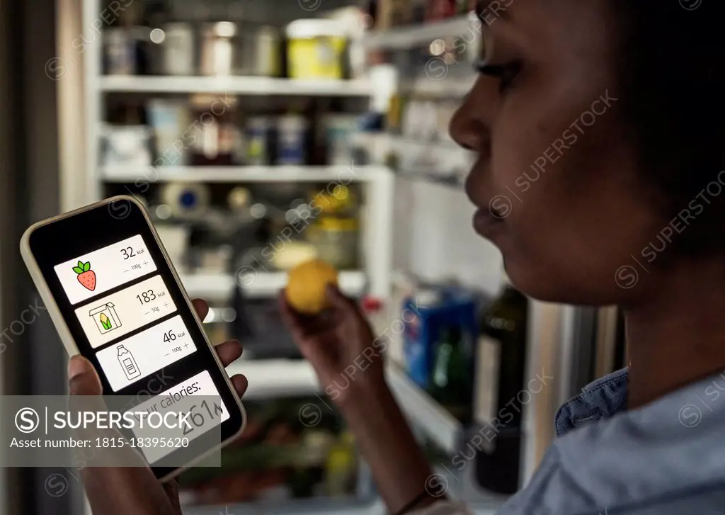 Woman counting calories through smart phone app at home