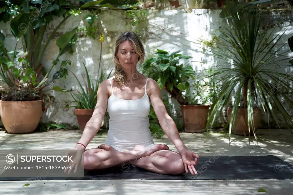 Mature woman meditating in lotus positing on exercise mat